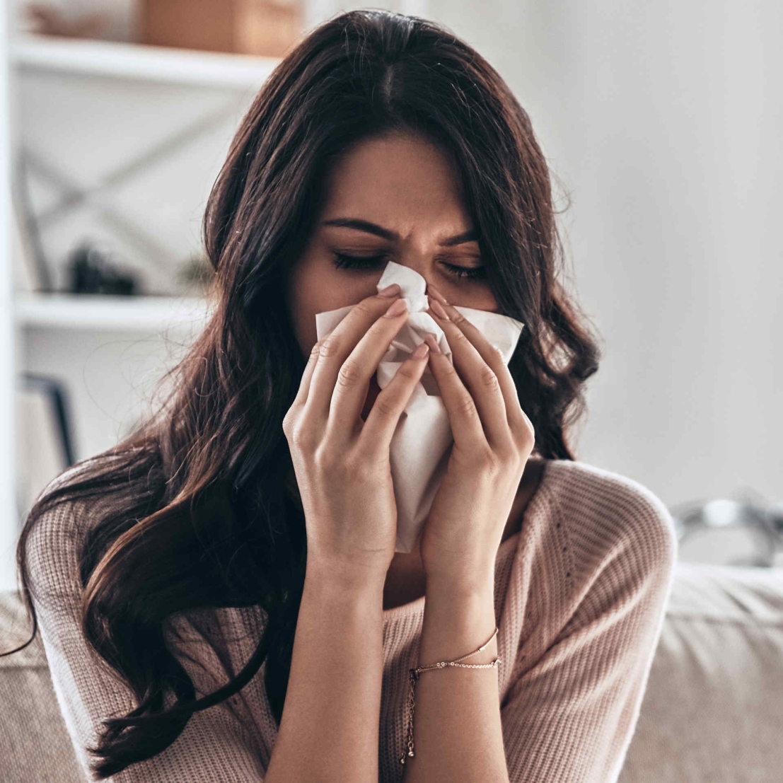 Une femme d'Asie du Sud malade, assise avec un mouchoir sur son nez en raison d'une allergie.